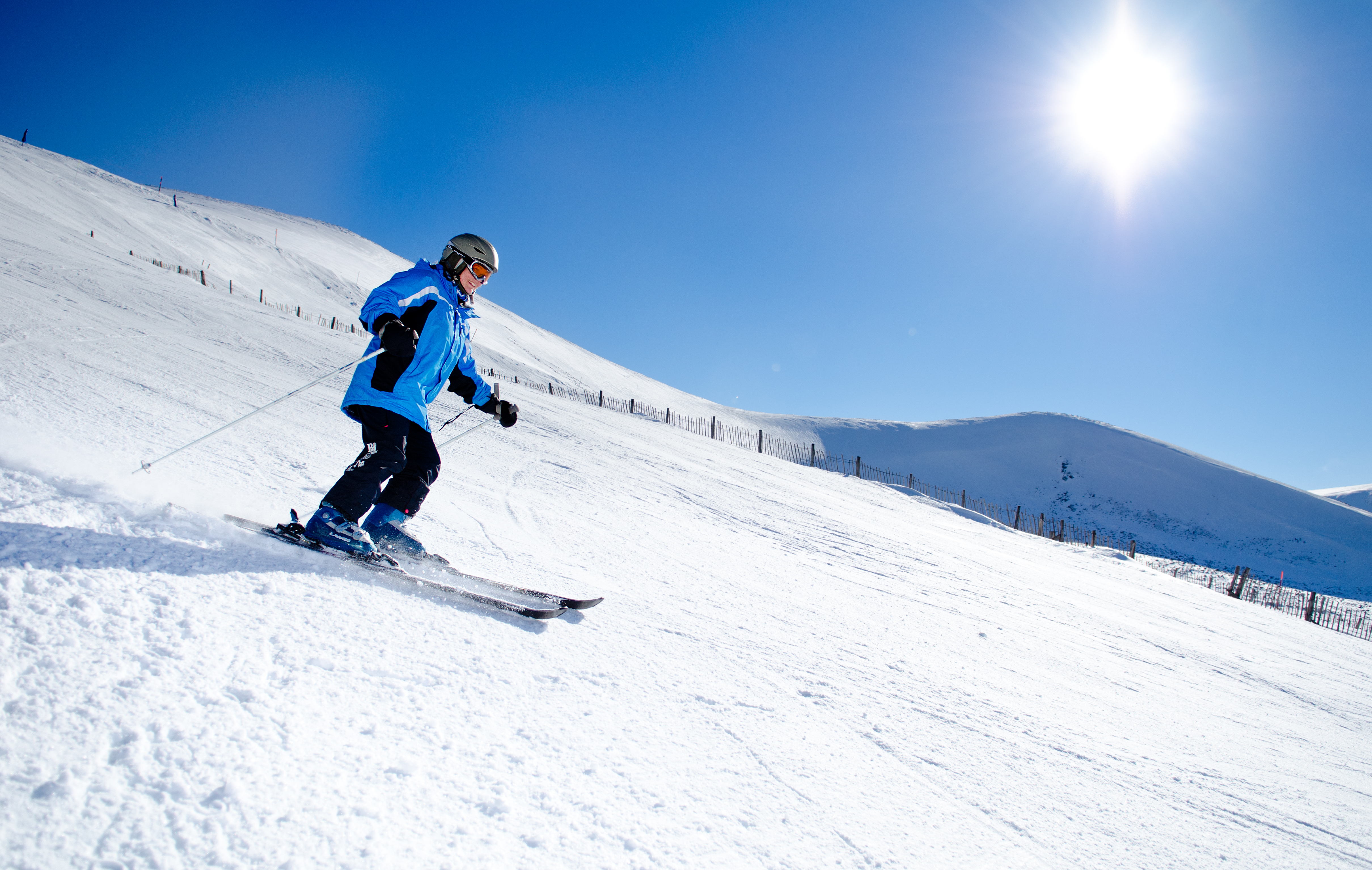 Skier gliding down the snowy mountain with bright blue sky on Cairngorm