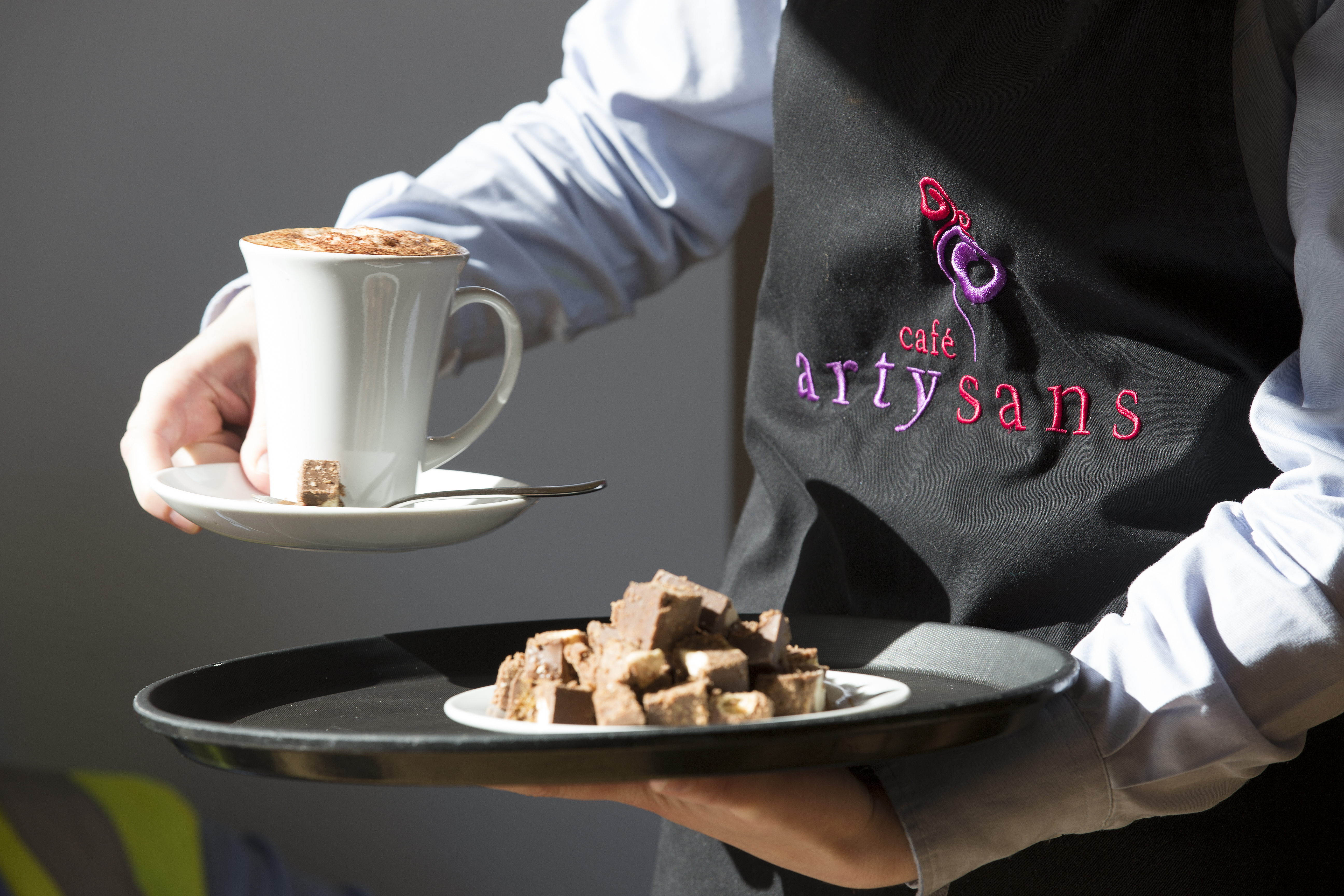 Waiter serving coffee and traybakes