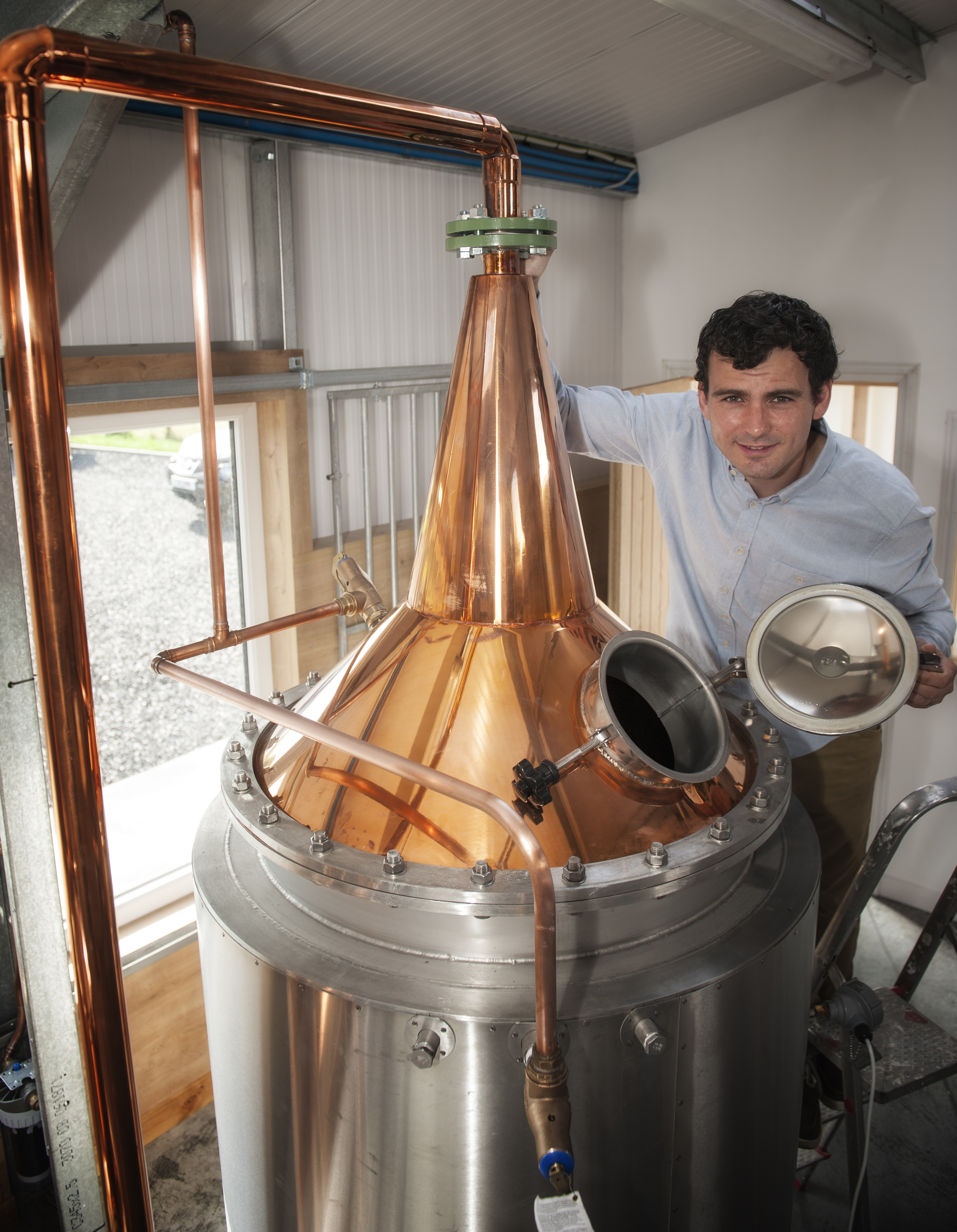 Man standing by gin still at Dunnet Bay Distillery